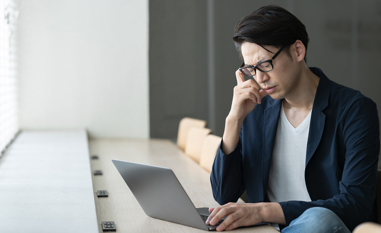 パソコンを見ながら悩んでいる男性